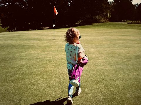 Toddler with golf bag on golf course